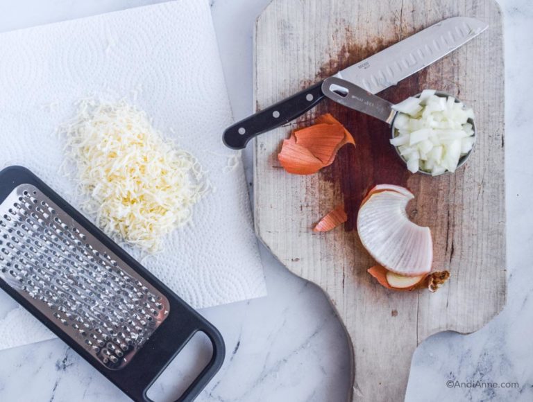 grater, grated cheese, chopped onion on cutting board with knife