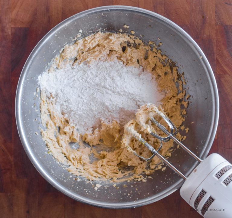 dry flour mixture poured onto wet ingredients with hand mixer beside