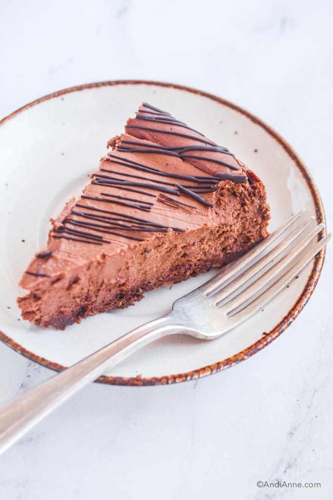 Slice of chocolate cheesecake on plate with a fork. 