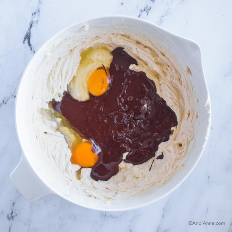 creamed cream cheese, eggs and melted chocolate in white bowl