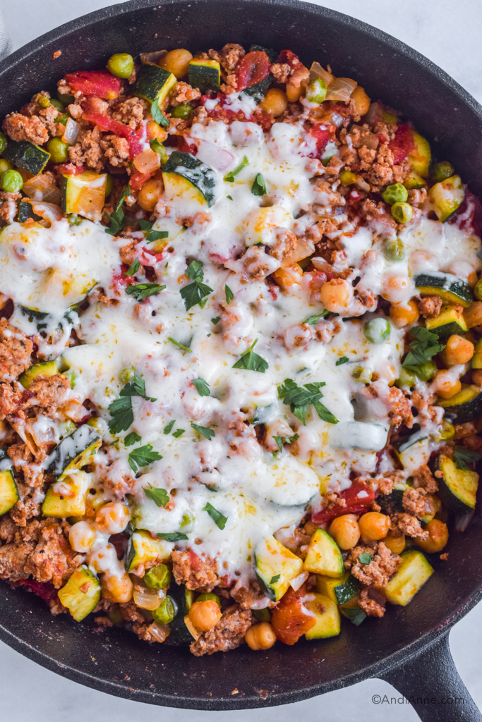 Looking down at skillet with ground turkey zucchini chickpea recipe with melted mozzarella on top.