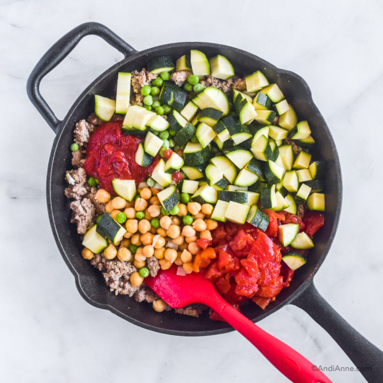 chopped zucchini, chickpeas, tomatoes on top of ground beef mixture in skillet