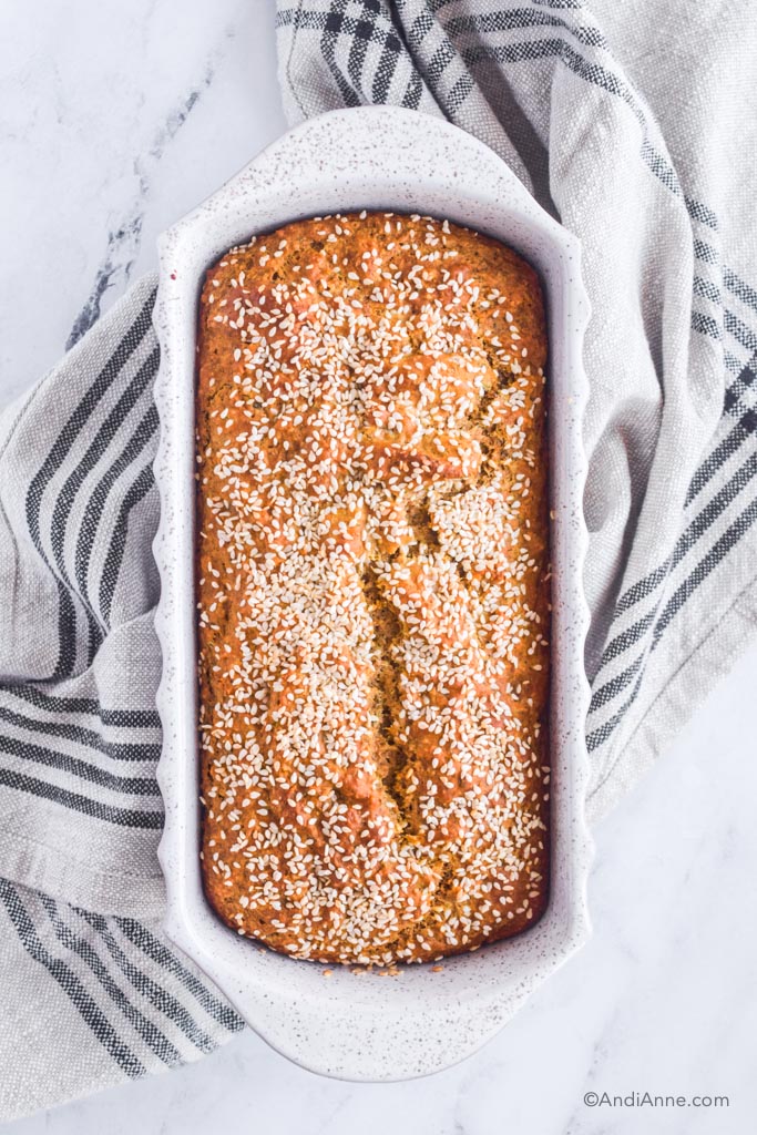 herbed quick bread in white loaf pan with kitchen towel underneath