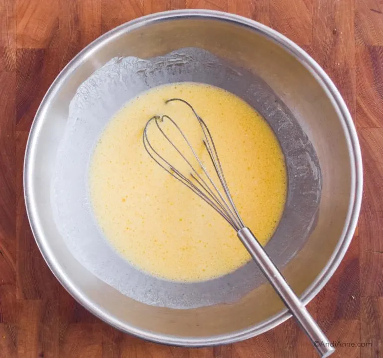 egg and milk in steel bowl with whisk