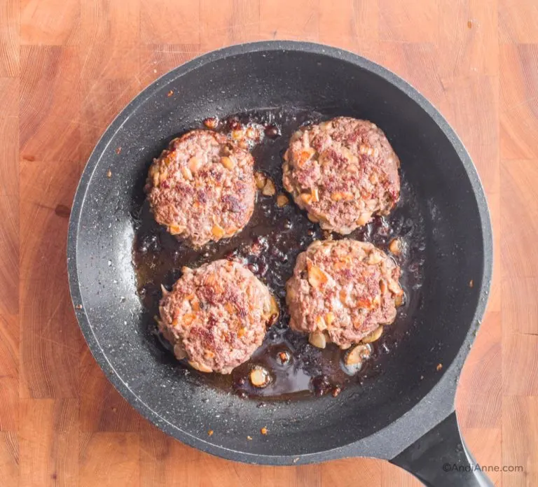 four cooked mushroom beef patties in a frying pan