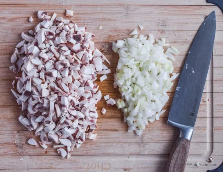 chopped mushrooms and chopped onon on a cutting board with a knife
