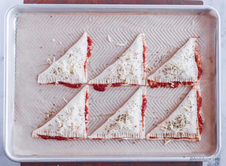 raw pizza pockets with oregano and shredded cheese on top