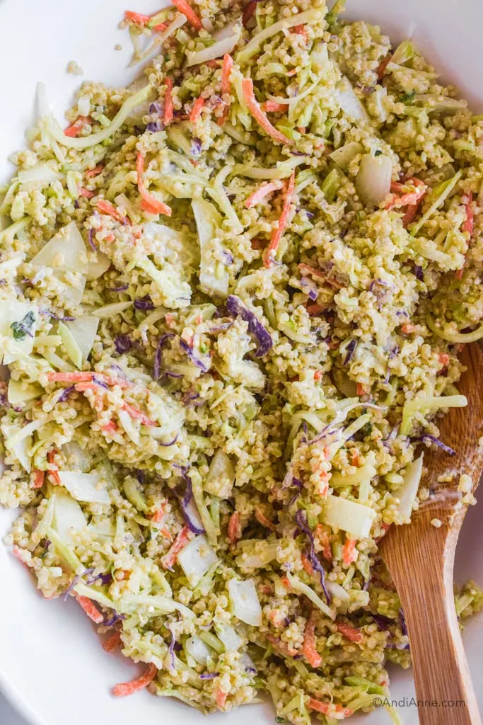 Close up of avocado quinoa coleslaw salad and wood spoon beside it