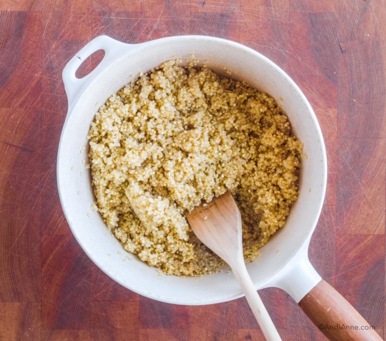 cooked quinoa in white pot with wood spatula