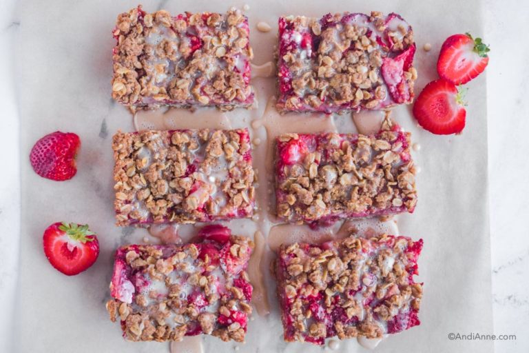 strawberry oat bars with glaze on top and sliced strawberries beside it.