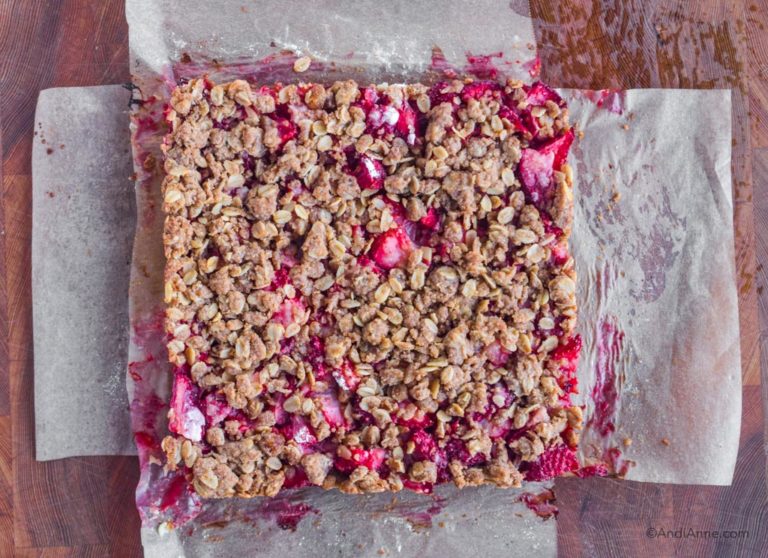 Baked strawberry oat bars removed from dish with parchment underneath