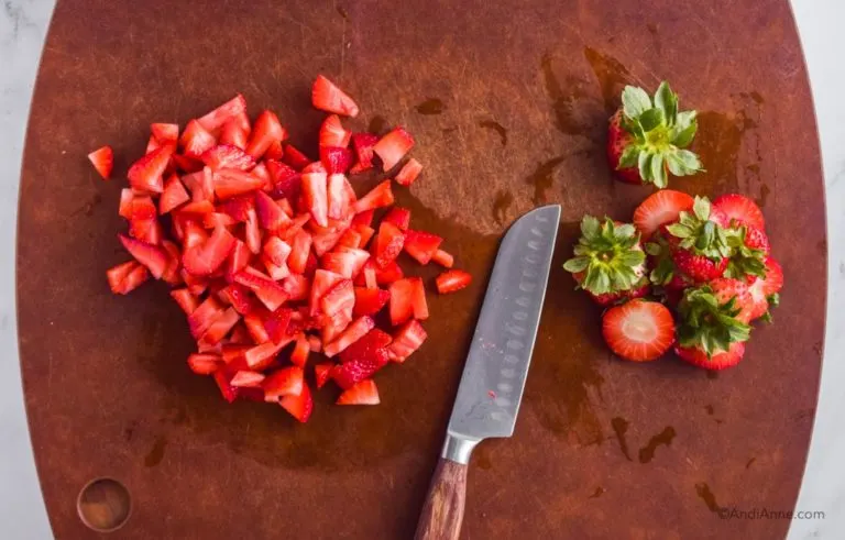 chopped strawberries with knife on cutting board
