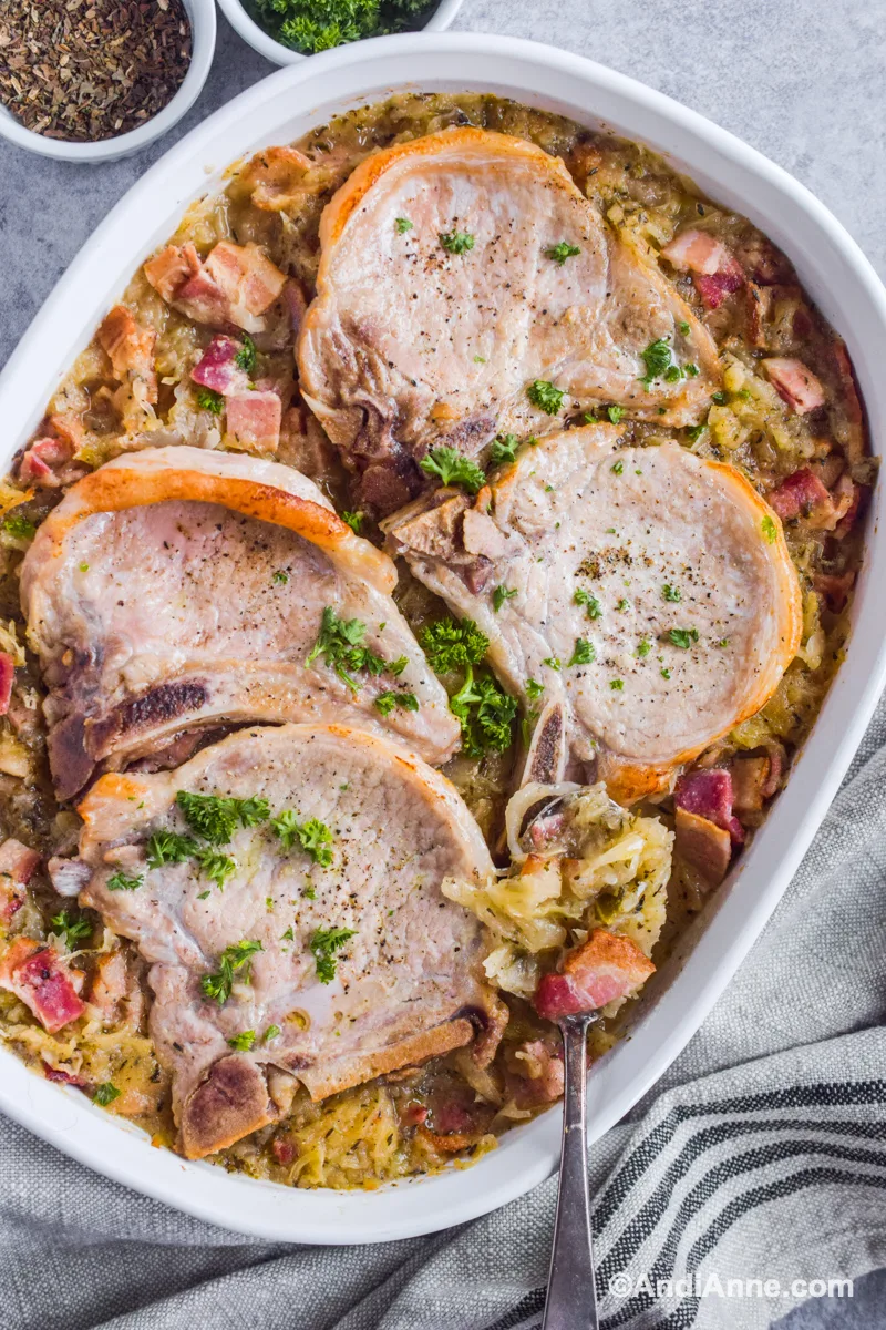 Pork chops and sauerkraut in white dish with spoon .