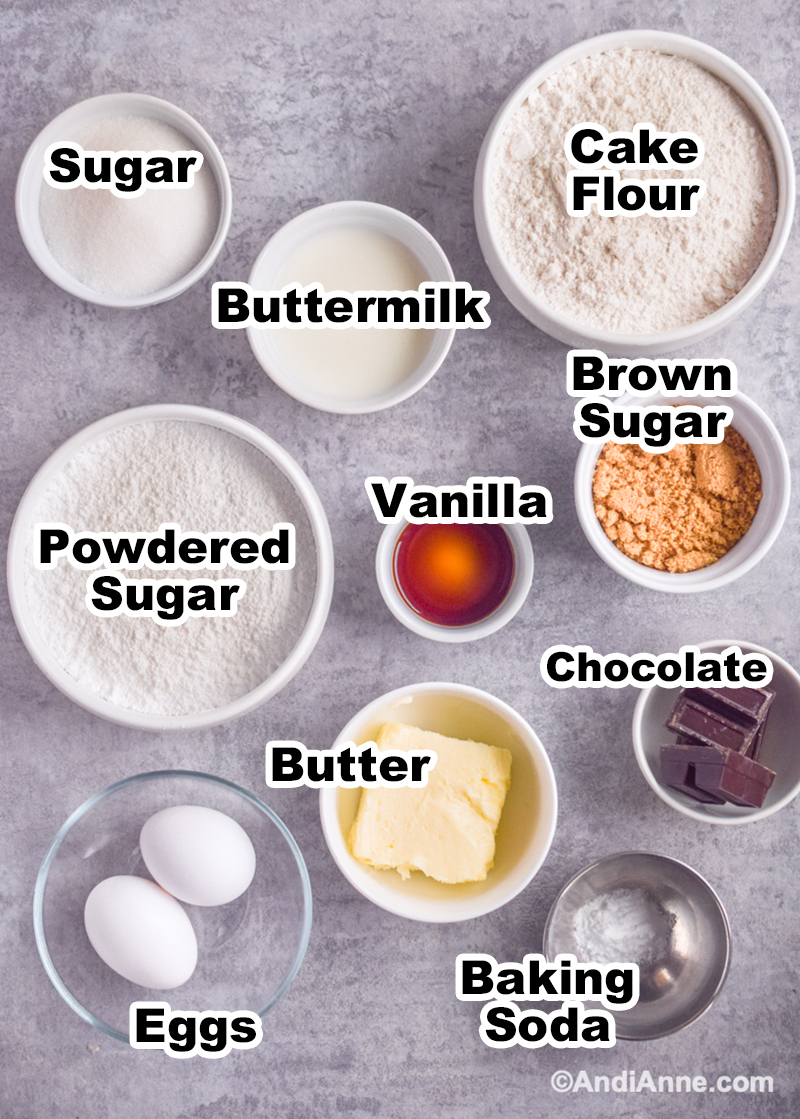 Ingredients to make the recipe including bowl of flour, bowl of powdered sugar, vanilla, brown sugar, bakers chocolate, butter and eggs.
