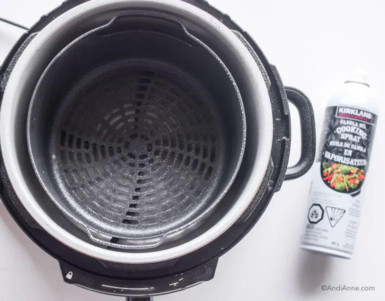 Looking down in an air fryer with cooking spray beside it.