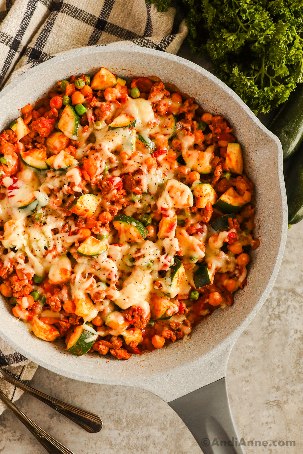 Frying pan with ground turkey zucchini chickpea recipe topped with melted mozzarella cheese.
