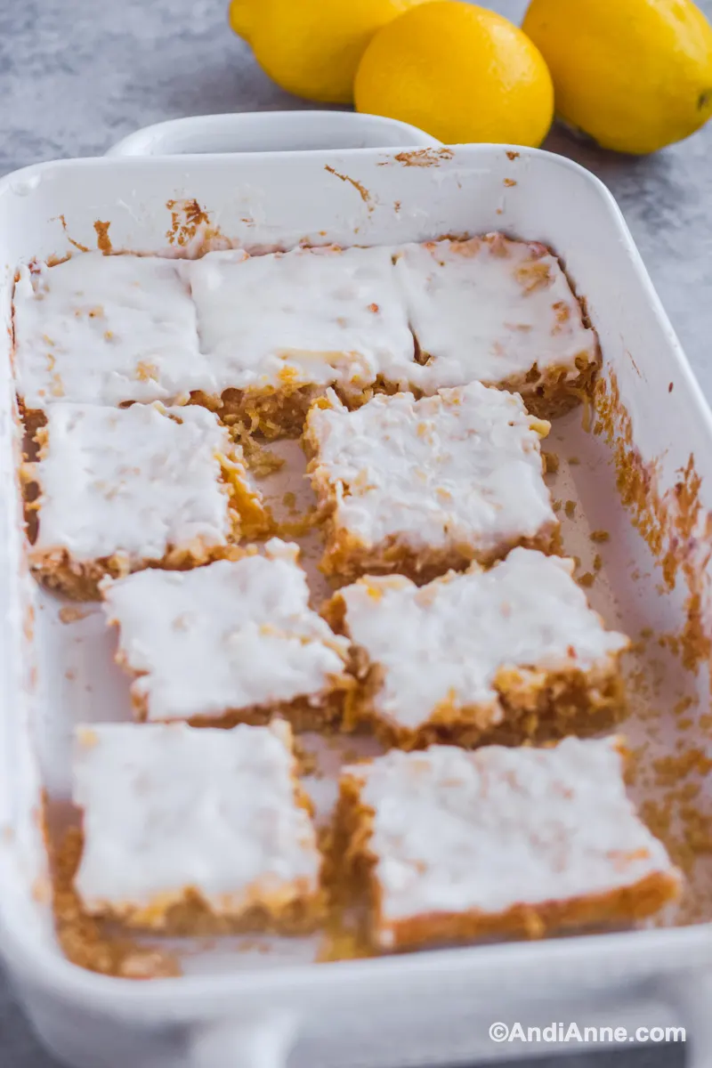 White baking dish with a few lemon coconut squares cut out and inside.