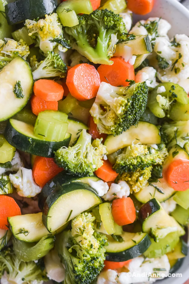 A close up of raw vegetables in salad including carrots, zucchini, broccoli and cauliflower.
