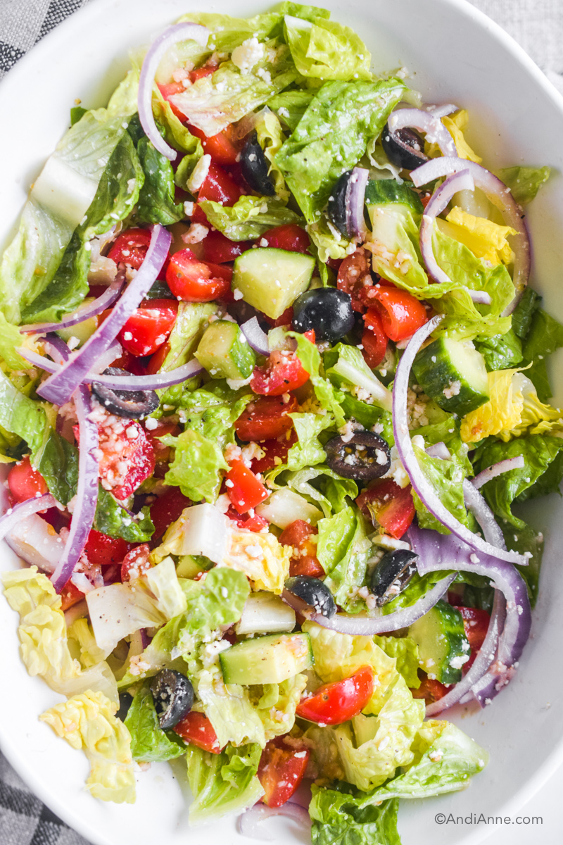 Looking down at the quick and easy greek salad recipe in a white oval bowl.