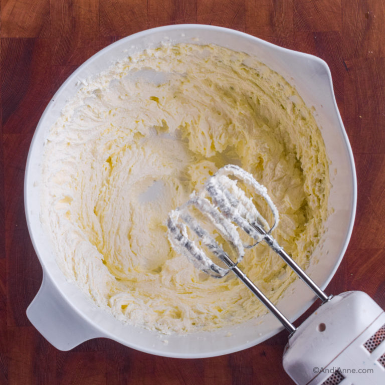 creamed butter and sugar in white bowl with hand mixer beside.