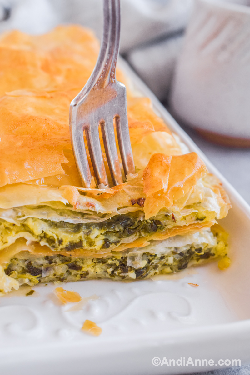 Close up of fork pushing into crispy phyllo dough and spinach filling.
