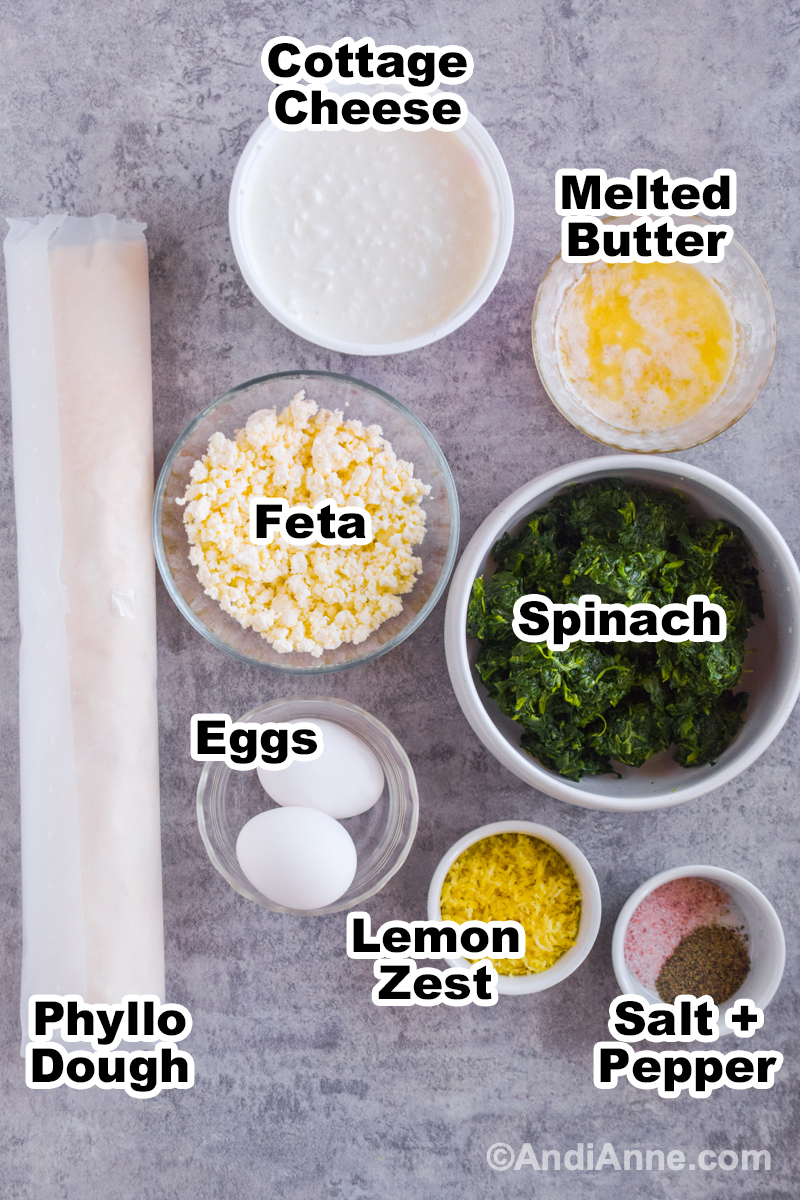 Ingredients to make the recipe including phyllo dough, bowl of feta, cottage cheese, melted butter, eggs, and spinach.