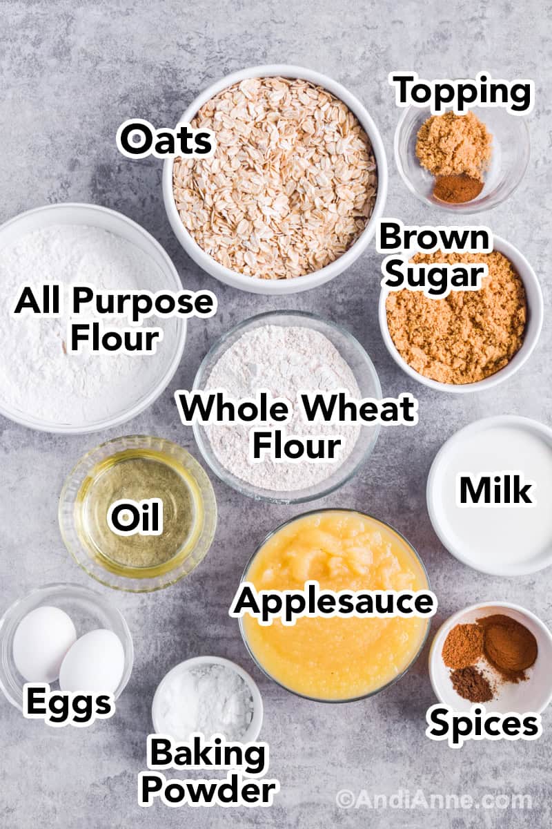 Looking down at recipe ingredients in bowls including rolled oats, flour, brown sugar, applesauce, milk, eggs and oil.