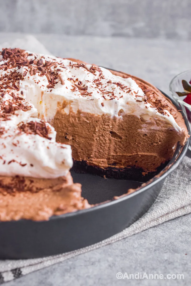 Close up of slice cut out of mocha pie plate with top whipped cream layer, middle creamy chocolate layer and bottom cookie crust layer.