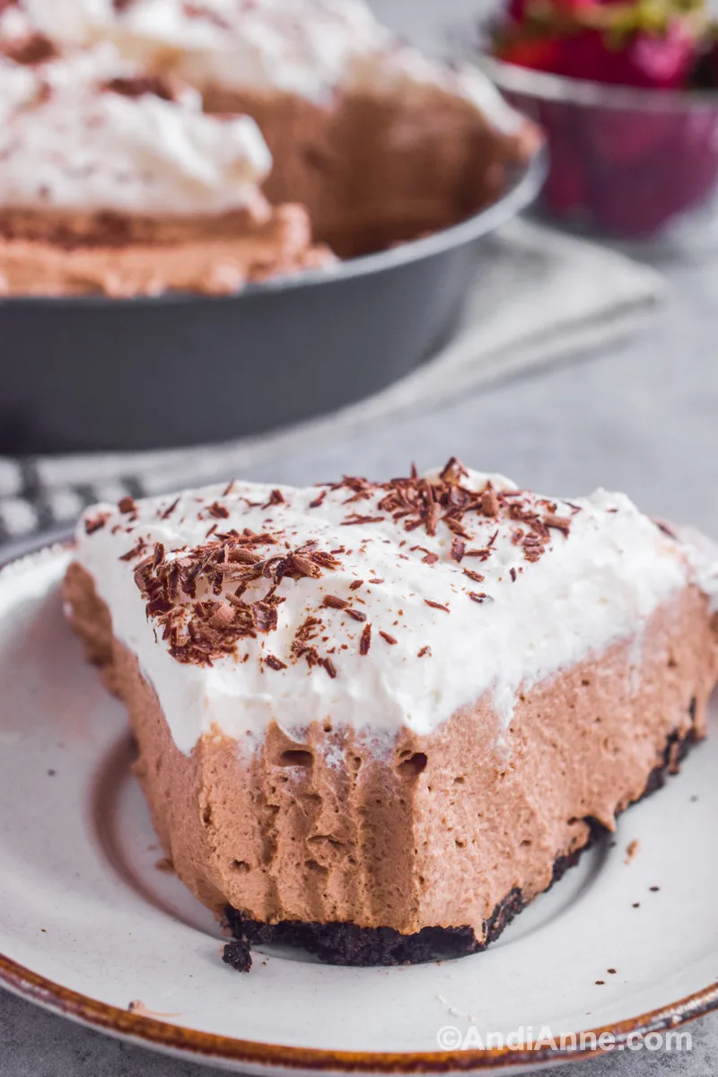 A slice of mocha pie on a plate with full dessert dish in background.