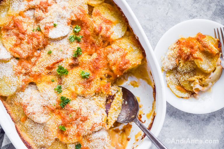 Au gratin potatoes in a casserole dish, with a serving scooped on to a small plate beside.