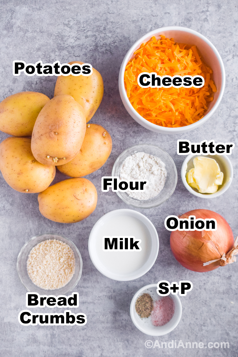 Recipe ingredients on counter including potatoes, bowl of shredded cheese, flour, milk, butter, onion and breadcrumbs.