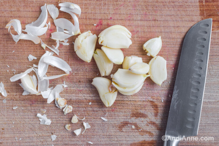 Peeled and mashed garlic on a counter with a knife.