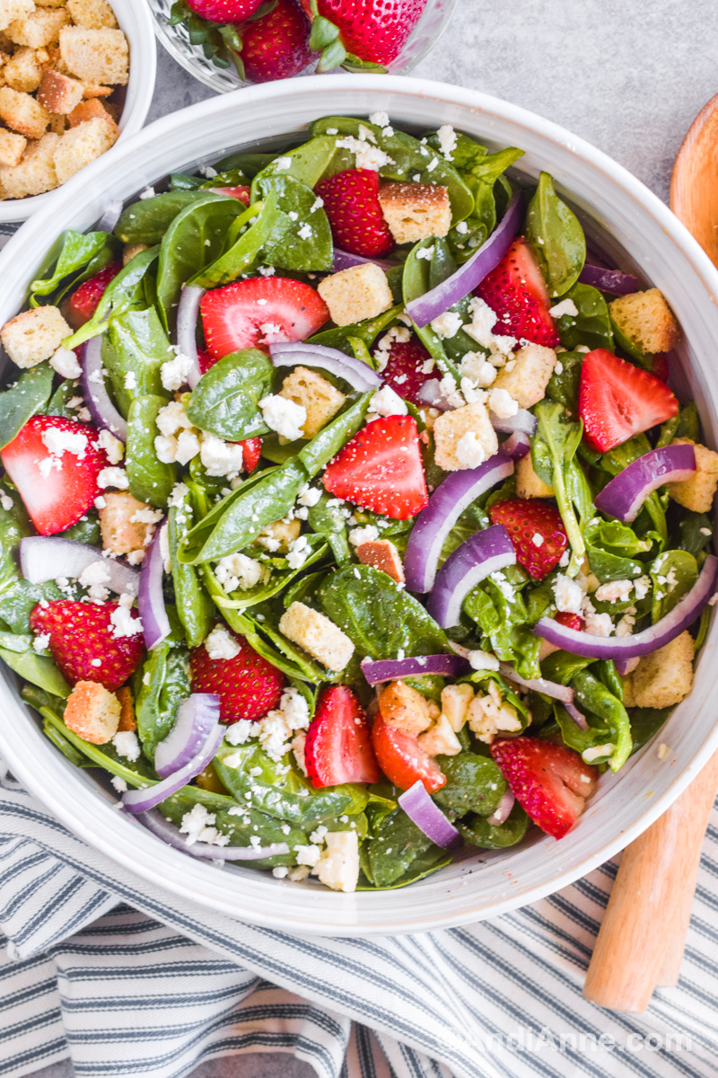 Close up of large bowl of strawberry spinach salad with feta and croutons.