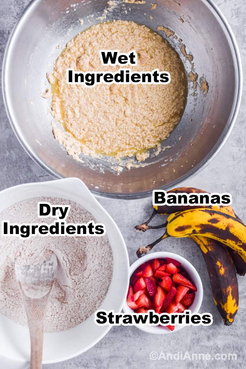 Bowl of wet ingredients, bowl of dry ingredients, bowl if sliced strawberries, bowl of ripe bananas.