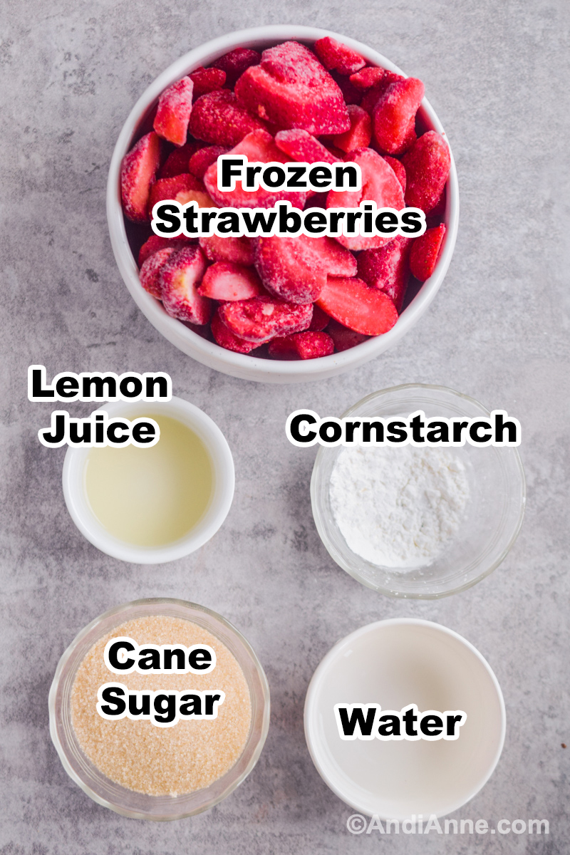 Ingredients to make recipe on the counter including bowl of frozen strawberries, bowl of lemon juice, bowl of cornstarch, cane sugar, and water.