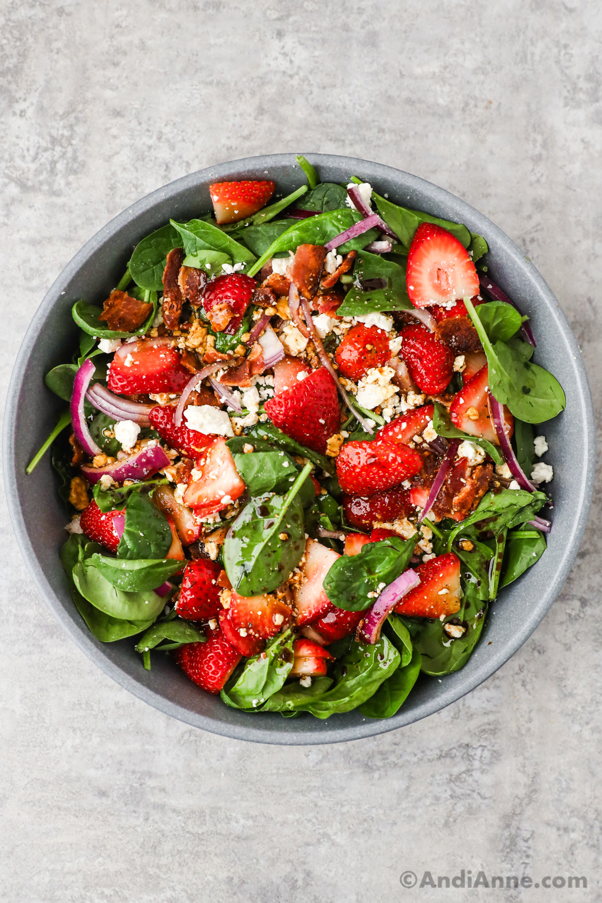 Salad dressing drizzled overtop of strawberry spinach salad.