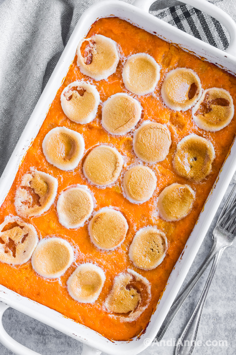 Sweet potato pineapple casserole with marshmallows with kitchen towel  and forks beside.