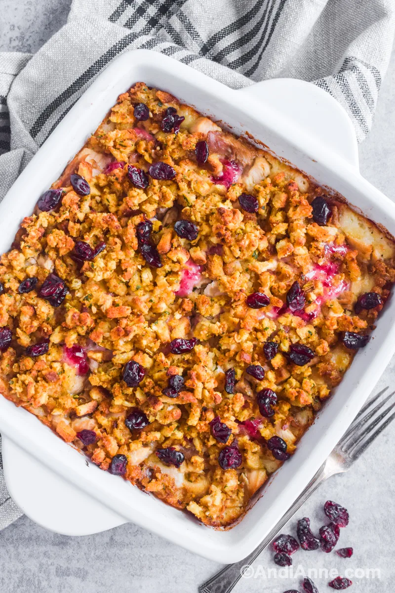 White square dish with turkey leftover casserole recipe surrounded by two forks and a kitchen towel.
