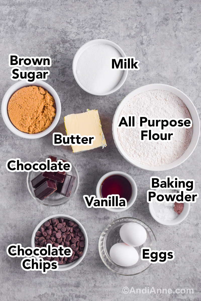 Recipe ingredients on the counter including a bowl with flour, bowl of brown sugar, butter, vanilla, chocolate, and eggs.