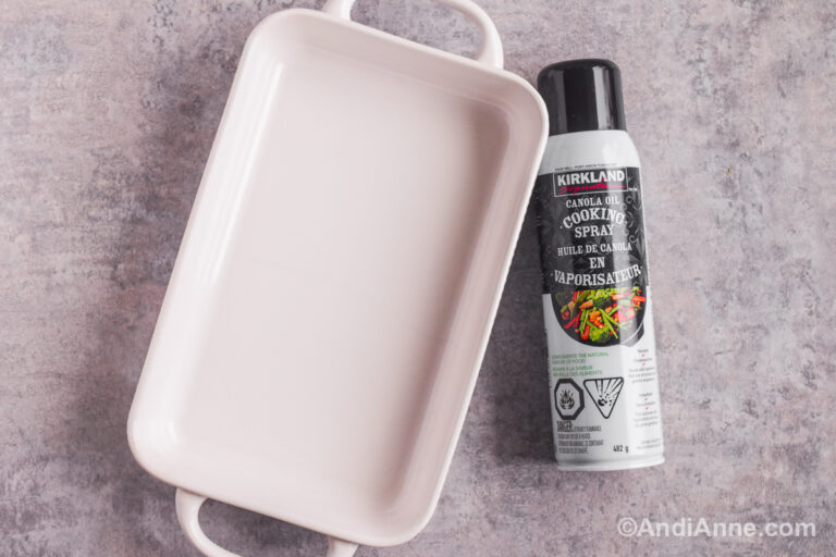 White rectangular baking dish and cooking spray on a counter.
