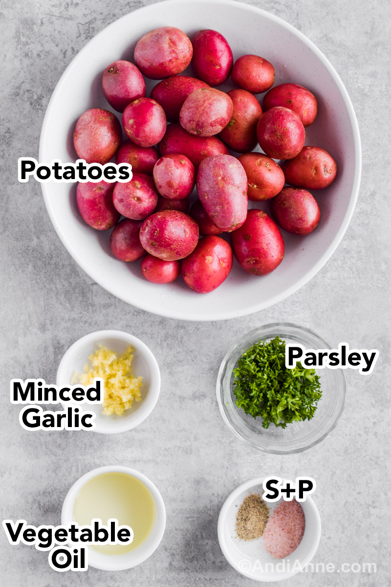 Recipe ingredients including bowl of baby red potatoes, bowls of minced garlic, chopped parsley, vegetable oil, salt and pepper.