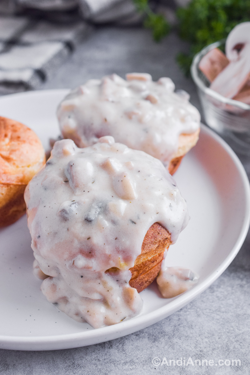 White creamy mushroom gravy poured on top of muffins on a white plate.