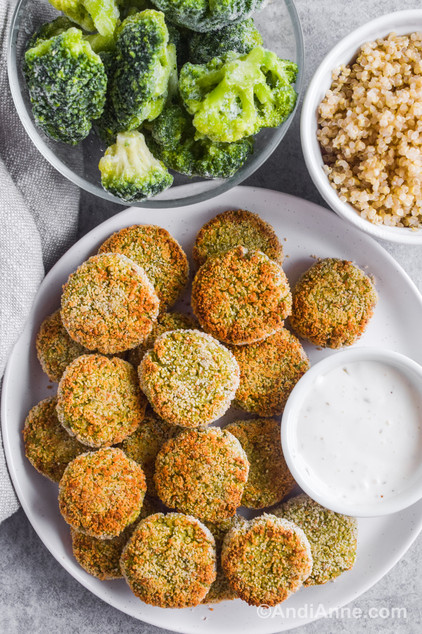 A plate of nuggets with a small bowl with ranch dressing. Bowls of frozen broccoli and cooked quinoa are beside the plate.
