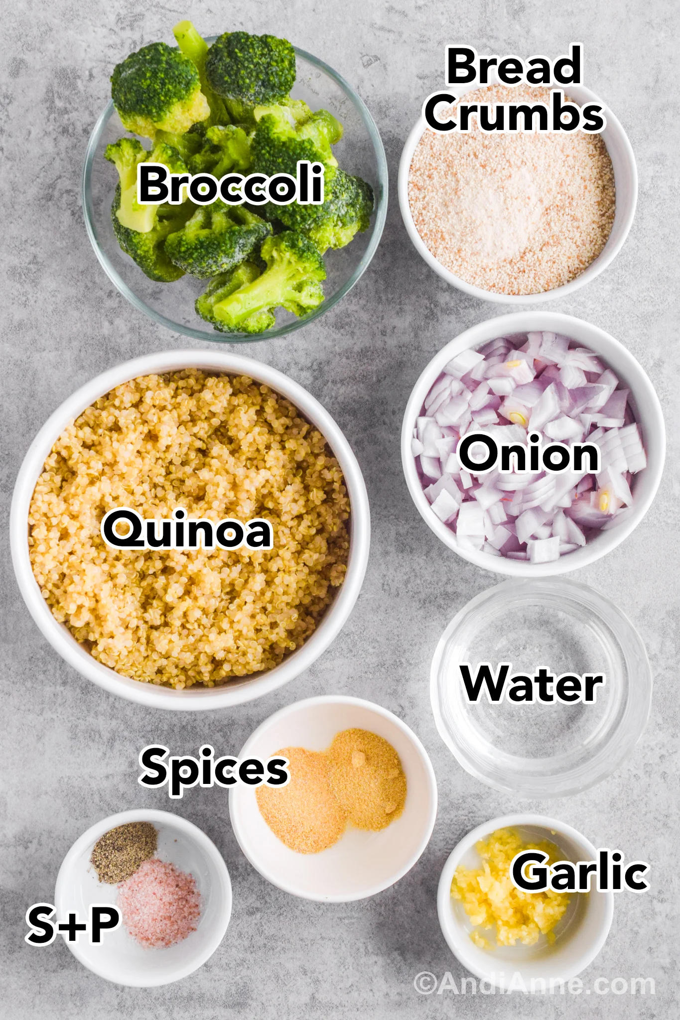 Recipe ingredients on a table including bowl of frozen broccoli, bowl of breadcrumbs, bowl of cooked quinoa, chopped onion, spices, and minced garlic.