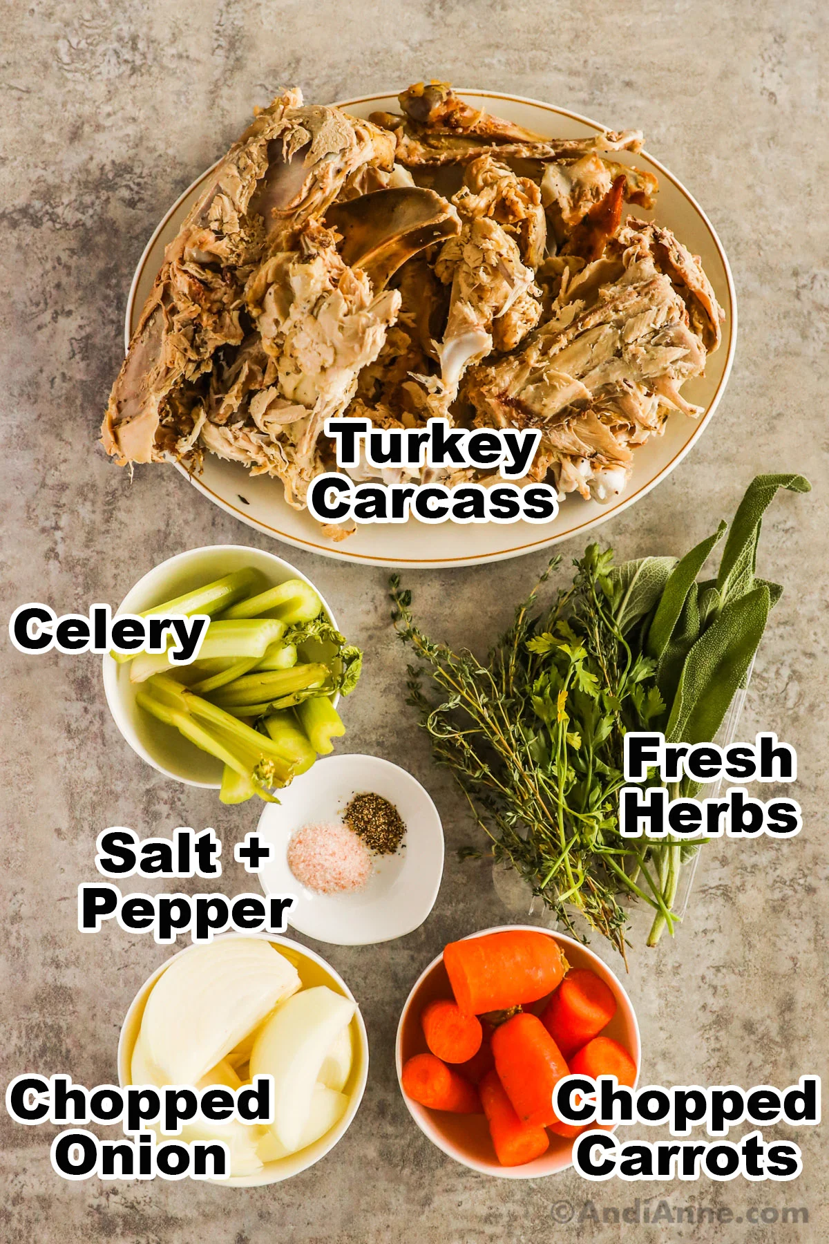Recipe ingredients including plate with turkey carcass, bowl of celery, fresh herbs, salt and pepper, chopped onion and chopped carrots.