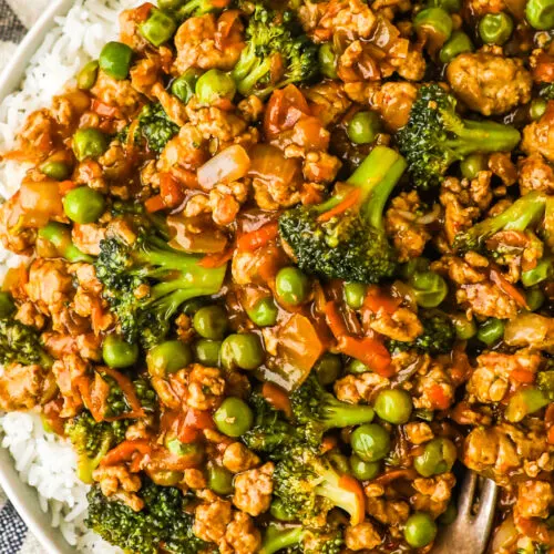 A plate with teriyaki ground turkey, broccoli and peas on a bed of white rice