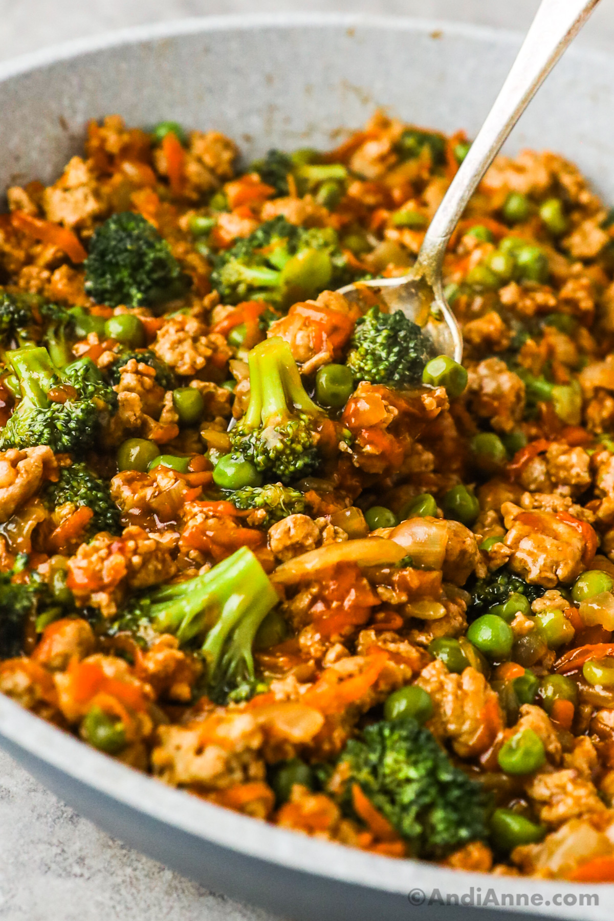Close up of cooked ground turkey teriyaki with broccoli, peas and shredded carrots.