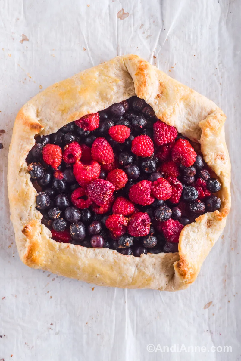 Looking down at a baked berry galette with fresh raspberries and blueberries in the center.