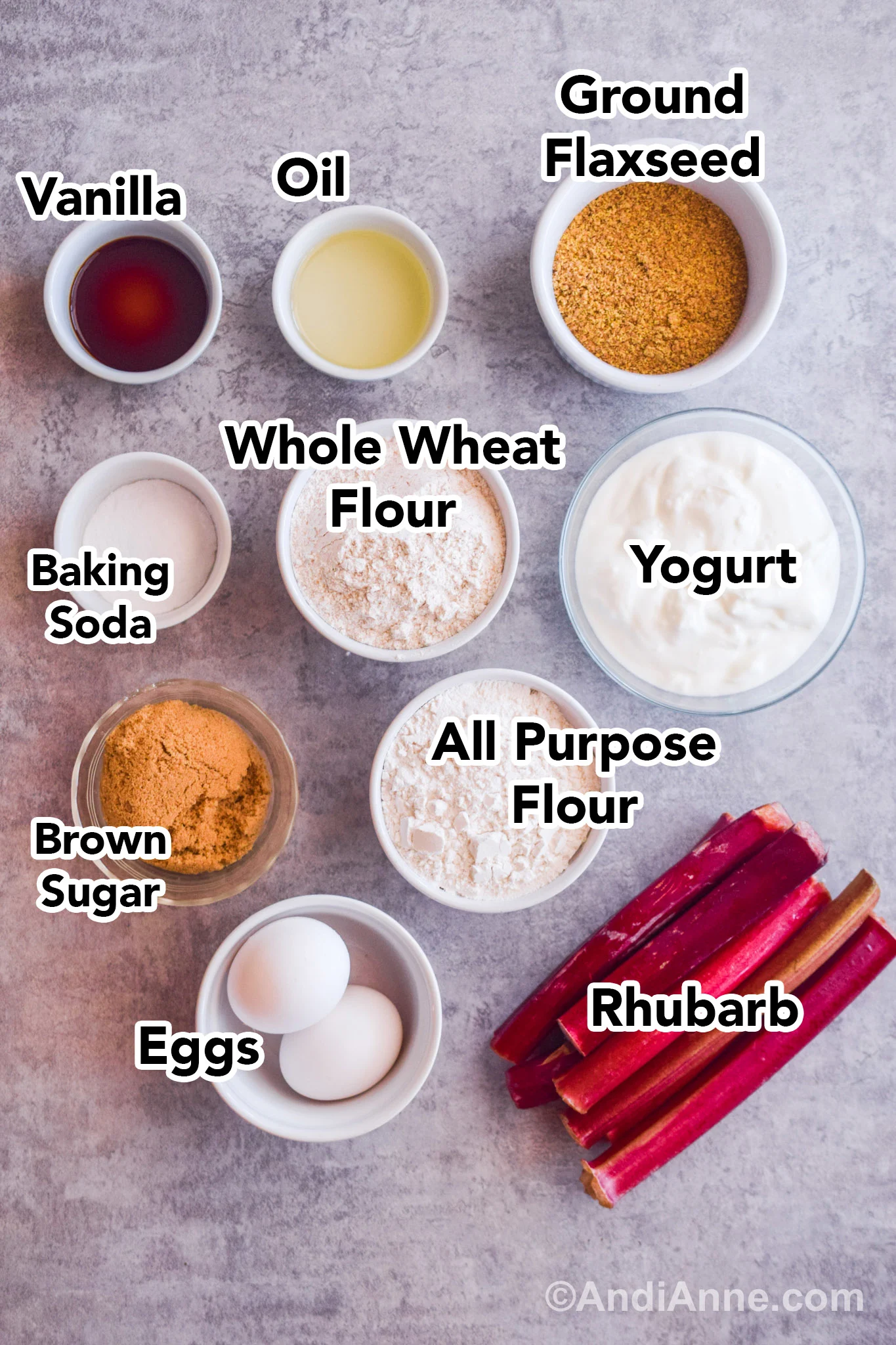 Recipe ingredients on table including bowls of yogurt, flours, brown sugar, eggs and sticks of rhubarb.