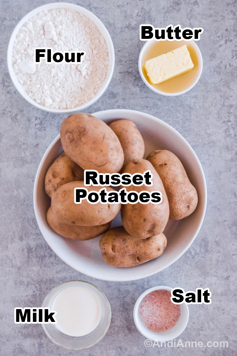 Recipe ingredients on the counter including a bowl with russet potatoes, bowls of flour, butter, milk and salt.